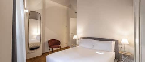 A bedroom with a large bed, a chair, a nightstand, and a wooden ceiling.
