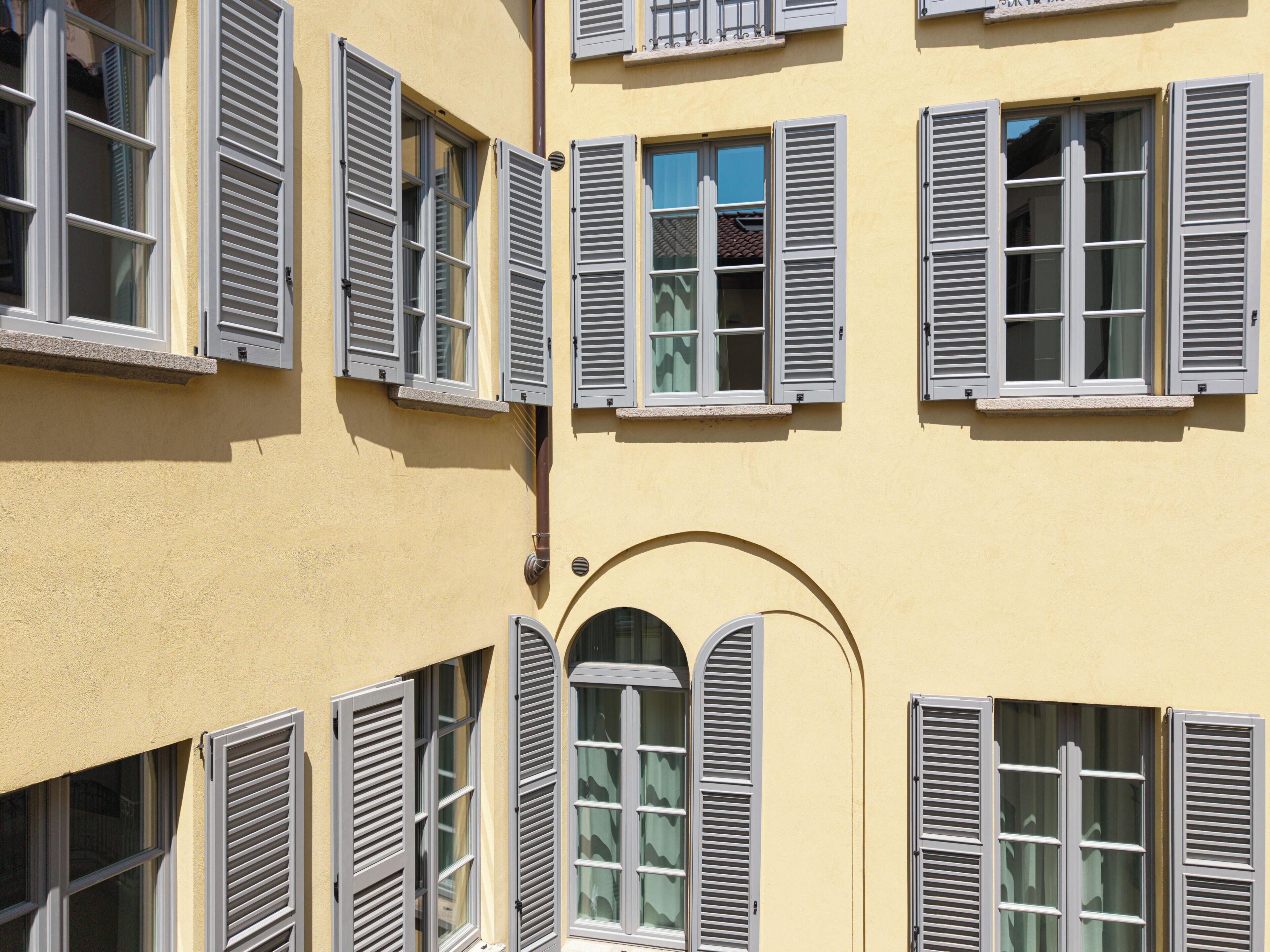 Fachada de edificio con múltiples ventanas y persianas.