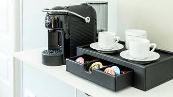 Angolo caffè con una macchina da caffè, tazze e un contenitore con diversi oggetti.