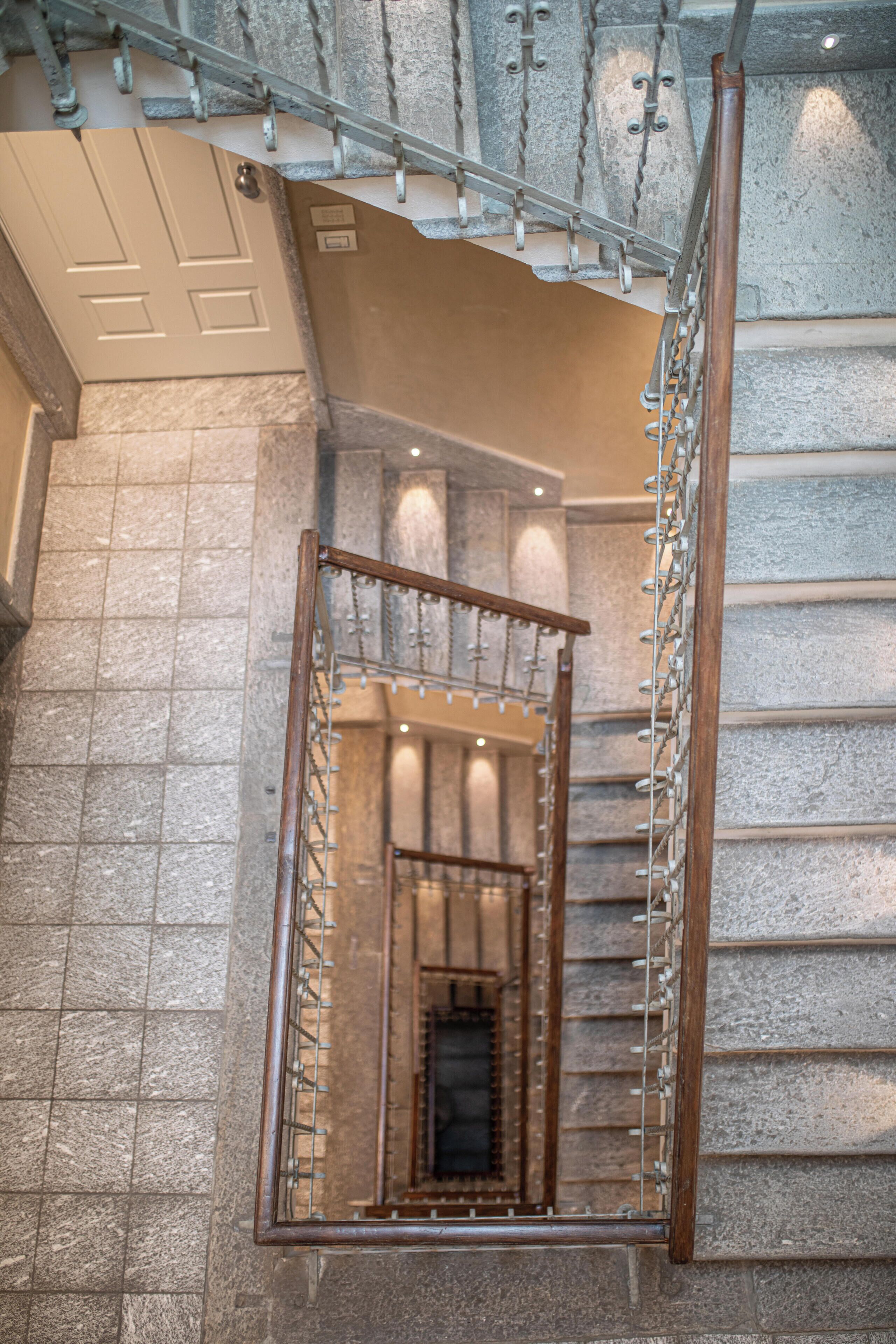 A staircase with a metal railing and a wooden handrail, leading to a lower level.