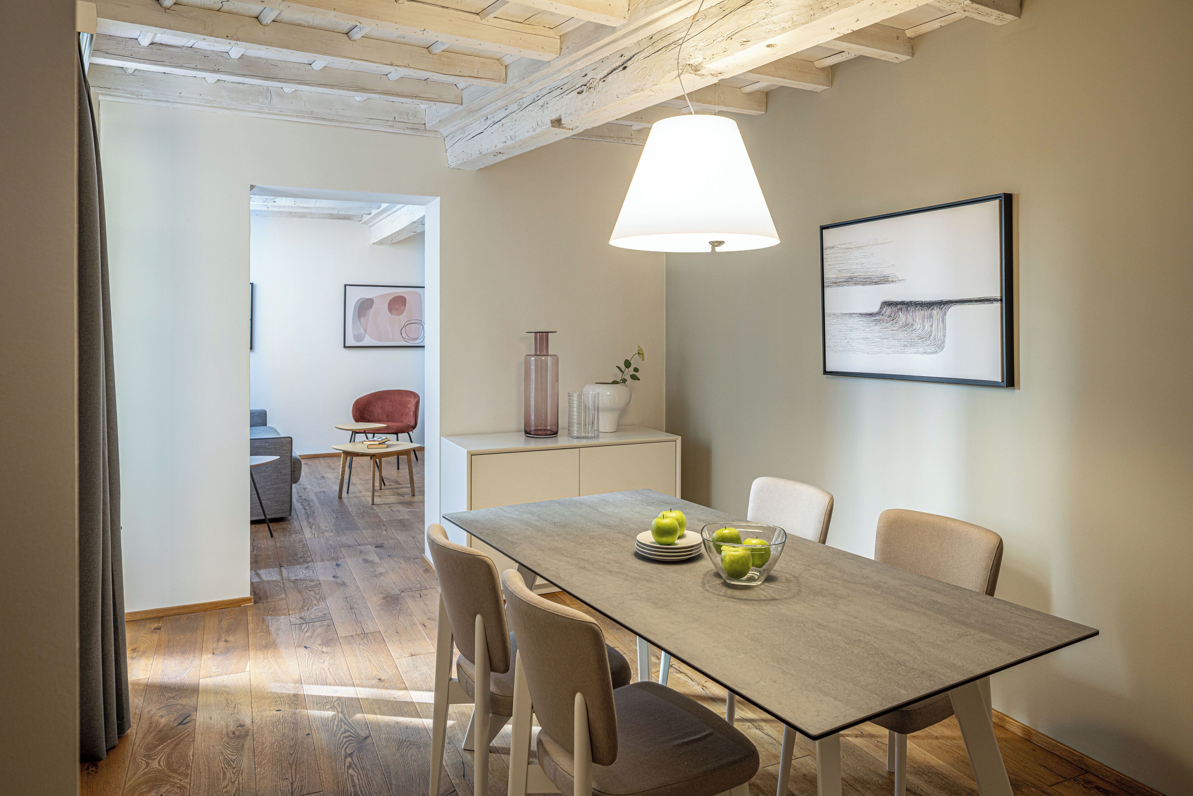 Un comedor con una mesa preparada para cuatro personas, una lámpara y un cuadro en la pared.