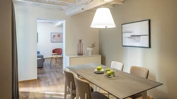 Un coin repas avec une table dressée pour quatre personnes, une lampe et un tableau encadré accroché au mur.