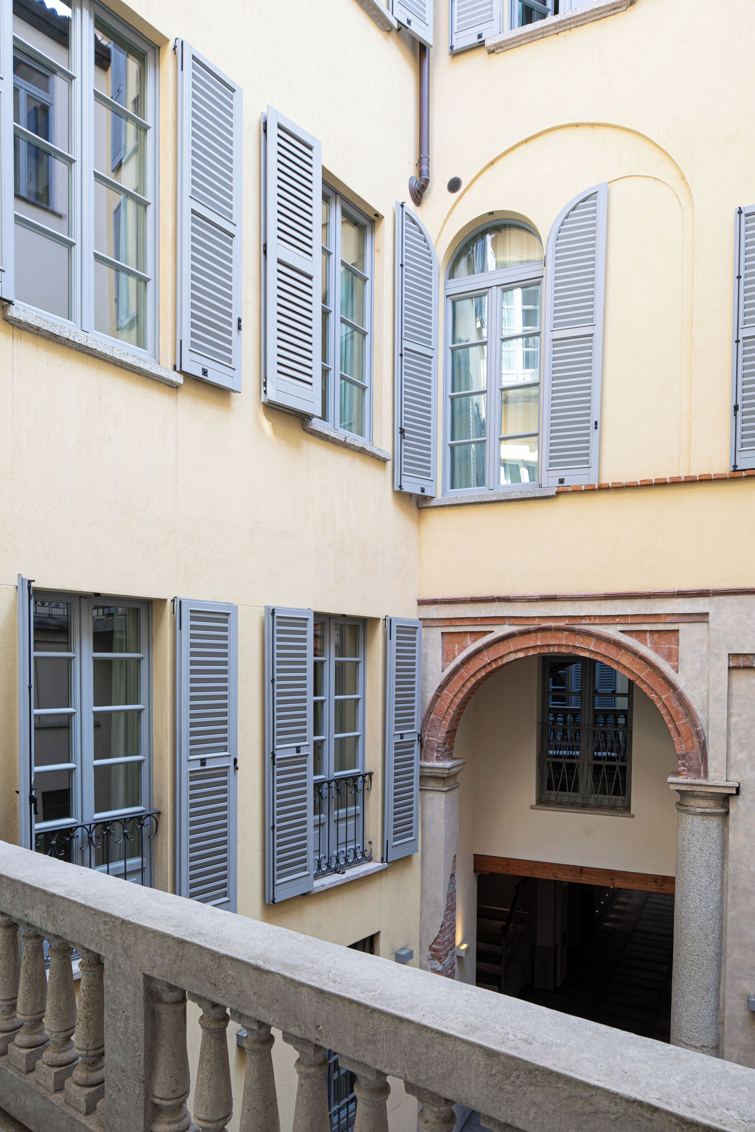 A building with multiple windows, some with shutters, and a stone balustrade.