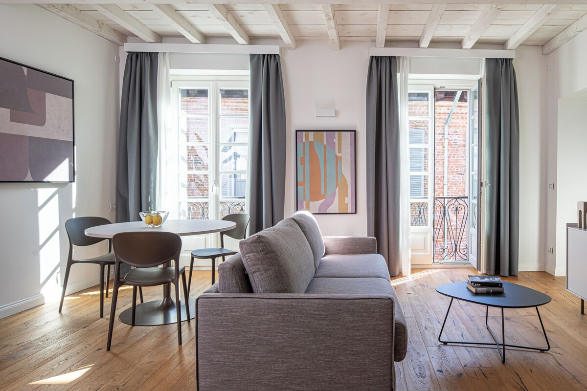 Una sala moderna con un sofá, una mesa de comedor, sillas y una pequeña mesa de centro.