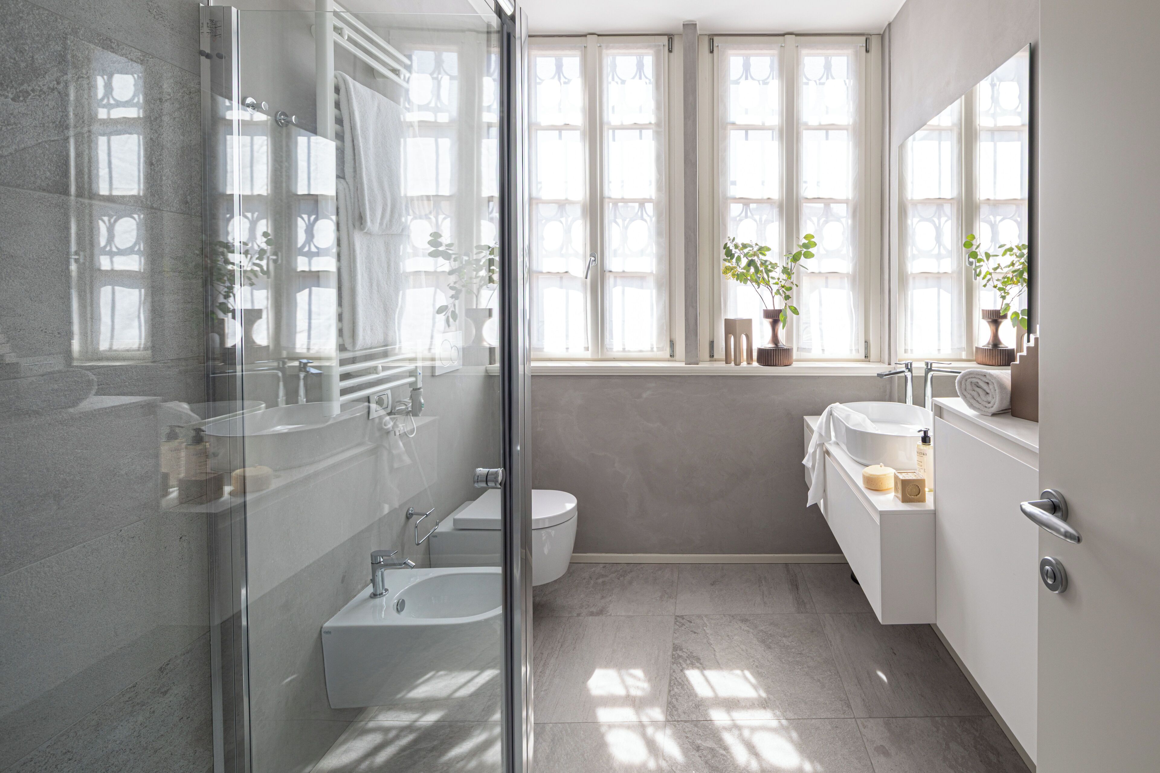 Une salle de bain moderne dotée d’une douche à parois de verre, d’une baignoire, de toilettes et d’un espace lavabo avec un miroir.