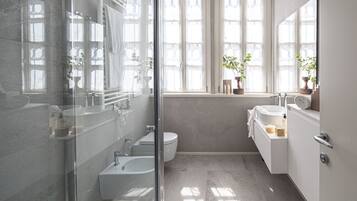 Une salle de bain moderne dotée d’une douche à parois de verre, d’une baignoire, de toilettes et d’un espace lavabo avec un miroir.