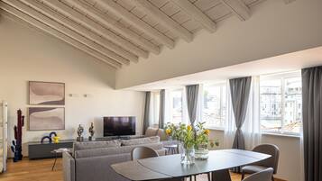 Una sala de estar moderna con sofá, mesa de comedor y televisor.