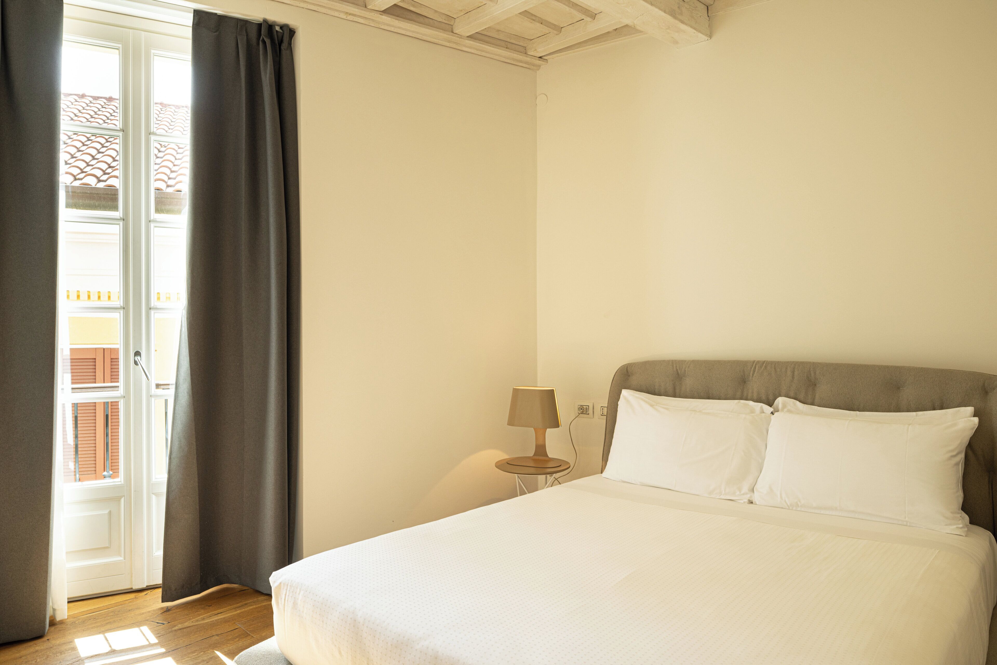 Una camera da letto con un letto, un comodino, una lampada e una finestra con tende.