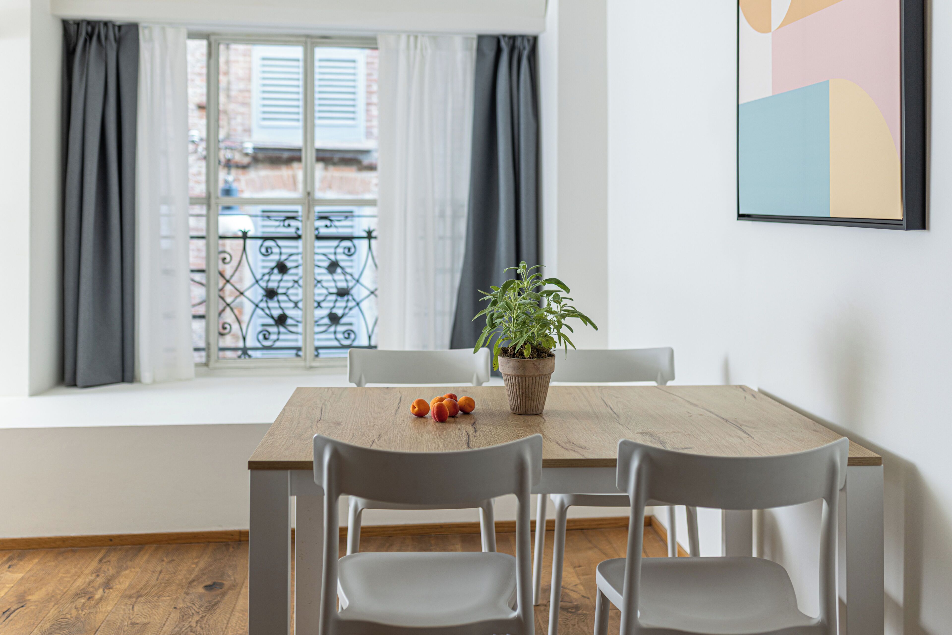 Un comedor con una mesa, sillas, una planta en maceta y vistas a un balcón con barandilla.