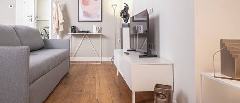 Un salon moderne avec un canapé gris, un bureau blanc et un plancher en bois.