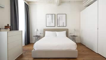 Une chambre à coucher au style minimaliste, avec un grand lit, deux tables de chevet dotées de lampes, une commode et deux œuvres d'art abstraites encadrées accrochées au mur.