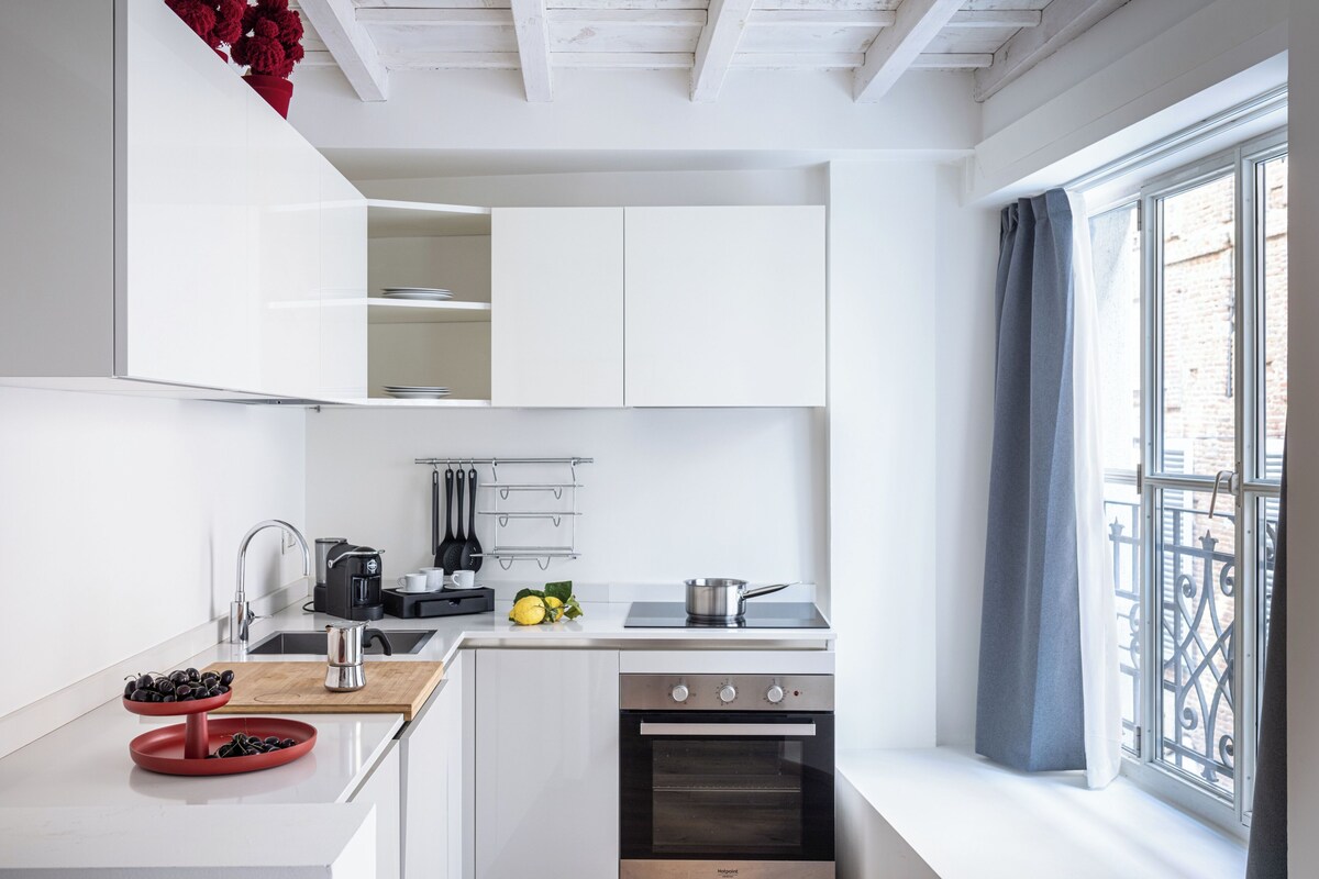 Una cocina moderna con armarios blancos, horno empotrado y ventana con vistas.