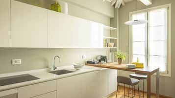 Une cuisine moderne avec des meubles blancs, un four encastré, un évier et un coin bar équipé de tabourets.