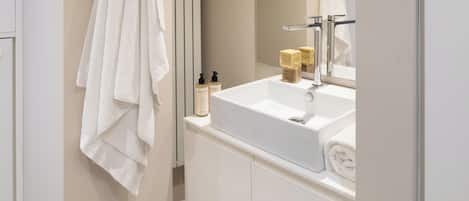 Une salle de bain moderne avec un lavabo blanc, un miroir et une serviette accrochée au mur.