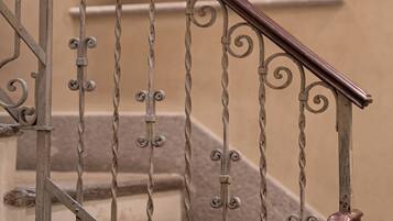 Eine Treppe mit aufwendiger Metallgeländerung und einem hölzernen Handlauf.
