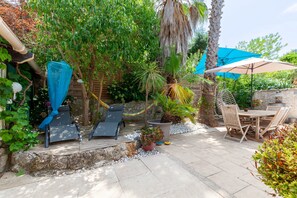 Um pátio com mesa e cadeiras de madeira, uma rede e um guarda-sol azul.