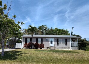 A single-story house with a covered porch, a garage, and a small front yard with grass and shrubs.