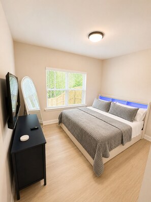 A bedroom with a bed, a TV, a small table, and a window with blinds. - Sleeps 7, 3BD 3BA, 8 minutes to Uptown (Charlotte)