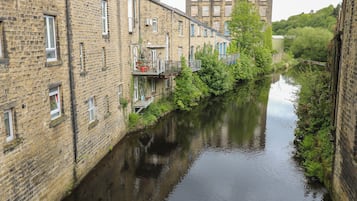 Un canal estrecho bordeado por edificios de ladrillo con balcones, un cielo despejado y un edificio distante.