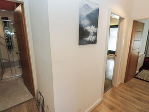 A hallway with a glass shower, a painting of a mountain lake, and a wooden floor. - No.1 Spa Mill Lodge (Huddersfield)