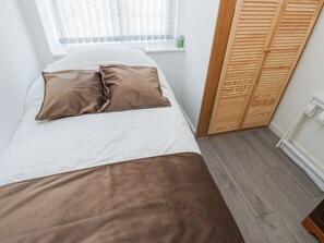 A bed with white and brown bedding, a window with blinds, a wooden closet, and a white radiator. - No.1 Spa Mill Lodge (Huddersfield)