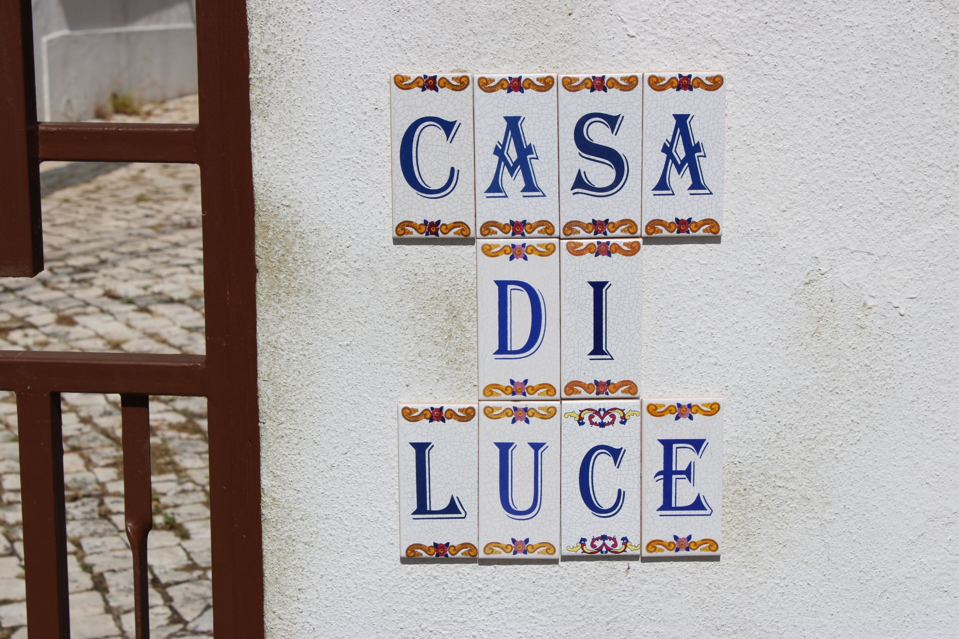A wall with decorative tiles spelling out 'CASA DI LUCE' in blue letters with ornate borders.