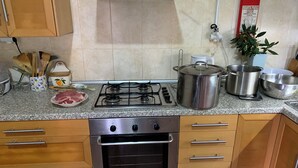 A kitchen with a gas stove, oven, and various cooking utensils.