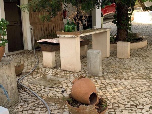 Une cour avec un sol en pierre, une porte en bois, un banc et des plantes en pot.