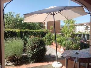 A patio area with a table and an umbrella, surrounded by well-maintained hedges and plants. - Via della Musica - One Bedroom House, Sleeps 3 (Vicchio)