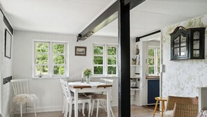 Une pièce comprenant une table à manger, des chaises, un canapé en osier et un buffet.
