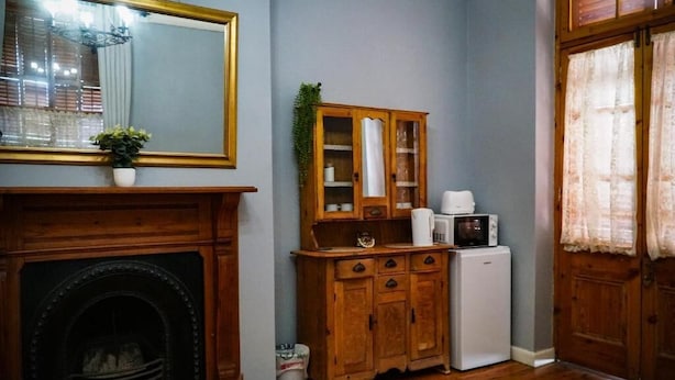 Une pièce avec une cheminée, un meuble en bois, un four à micro-ondes et une porte avec des rideaux.