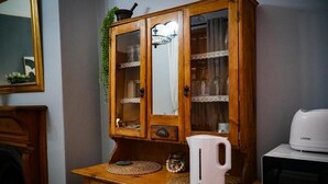 Un meuble en bois avec des portes en verre, une bouilloire électrique blanche et un four à micro-ondes posés sur un comptoir en bois.