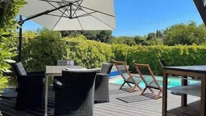 An outdoor deck with a pool, lounge chairs, and a table. - Villa with heated pool in Toscana (San Quirico)