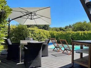 Eine Terrasse im Freien mit Pool, Liegestühlen und Tisch.