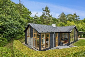 A modern house with large windows, a stone foundation, and a wooden deck. - Architect-designed house in Mols Bjerge (Ebeltoft)