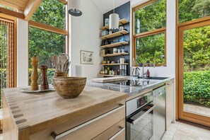 A modern kitchen with wooden countertops, a built-in oven, and a large window overlooking greenery. - Architect-designed house in Mols Bjerge (Ebeltoft)