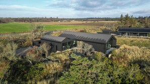 Ett modernt hus med ett stort glasfönster, omgivet av en vacker natur.