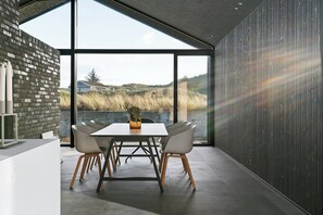 Ein moderner Essbereich mit großem Fenster, einer Ziegelwand und Blick ins Freie.