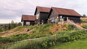 A rustic wooden house with a steep roof, surrounded by lush greenery and a fence. - Private cabin with stunning views near Oslo (Espa)