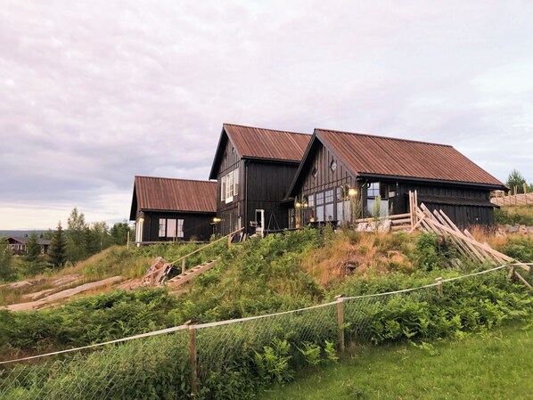 A rustic wooden house with a steep roof, surrounded by lush greenery and a fence. - Private cabin with stunning views near Oslo (Espa)