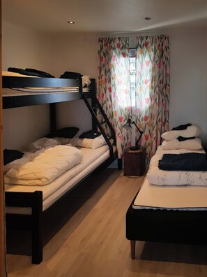 A dormitory room with bunk beds, a small table, and a window with floral curtains. - Private cabin with stunning views near Oslo (Espa)