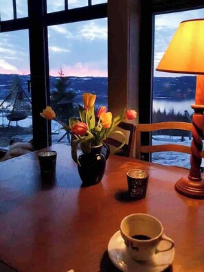 A table with a vase of flowers, a cup, and a lamp. - Private cabin with stunning views near Oslo (Espa)