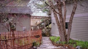 A pathway leading to a house with a wooden fence, a pergola, and a staircase. - The Artist's Loft | Pet Friendly | Close to Torch (Alden)