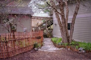Ein Weg führt zu einem Haus mit Holzzaun, einer Pergola und einer Treppe.