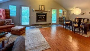 A spacious loft with a fireplace, a dining area, and a large window. - The Artist's Loft | Pet Friendly | Close to Torch (Alden)