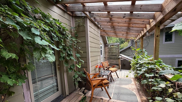 A wooden deck with a pergola, a table with chairs, and a potted plant. - The Artist's Loft | Pet Friendly | Close to Torch (Alden)