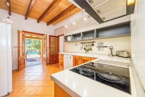 Eine moderne Küche mit Holzschränken, einem eingebauten Ofen und Blick ins Freie.