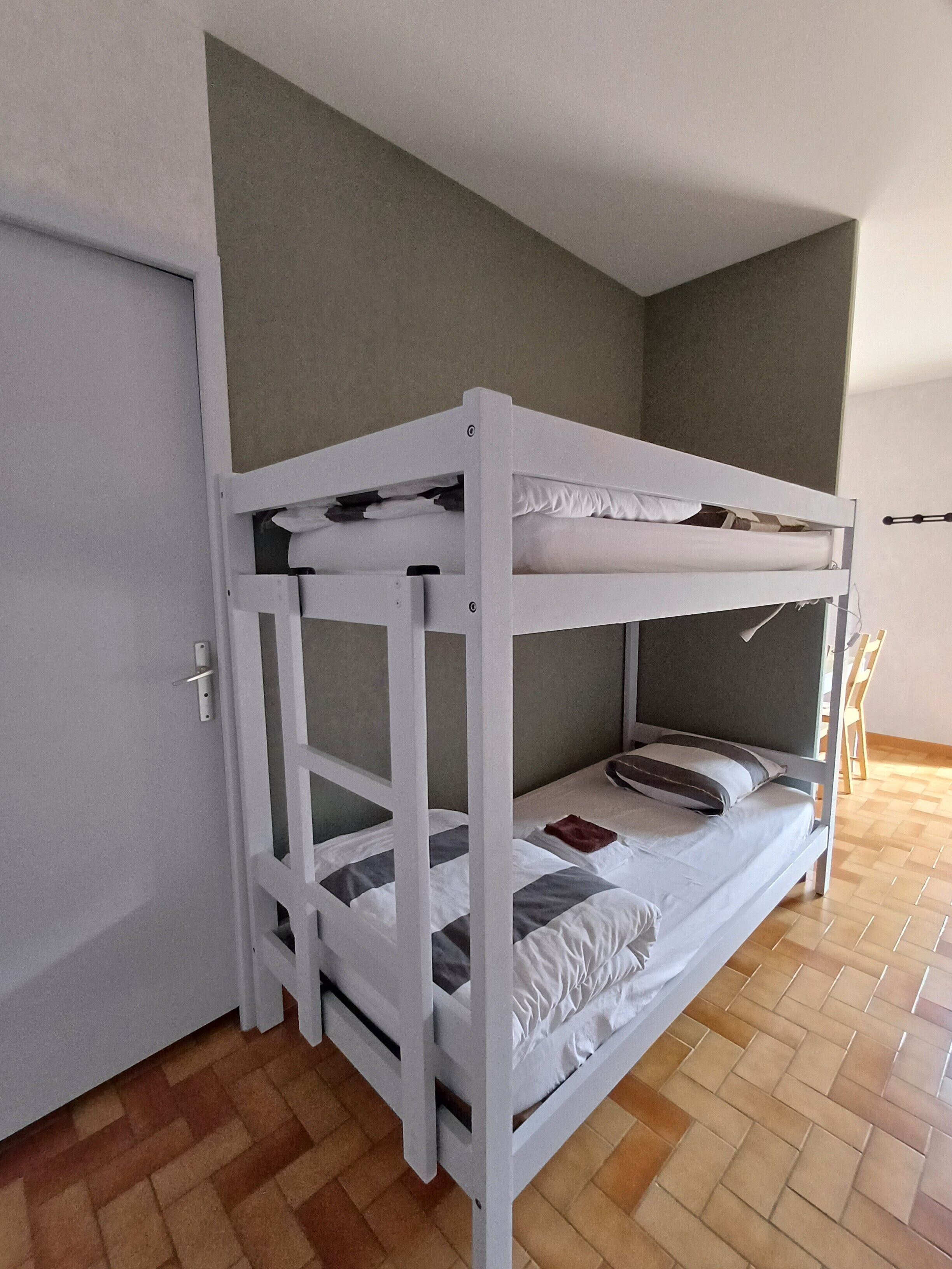 Una litera en una habitación con suelo de madera y una puerta.