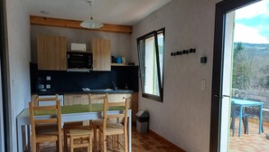 A compact kitchen with wooden cabinets, a microwave, and a dining area with a table and chairs.