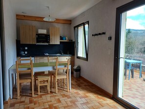 Eine kleine Küche mit Holzausstattung, einer Mikrowelle und einem Essbereich mit Tisch und Stühlen.